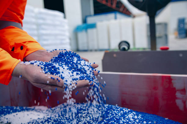 Krishna Plastic Manufacturing Process - Worker handling blue plastic pellets
